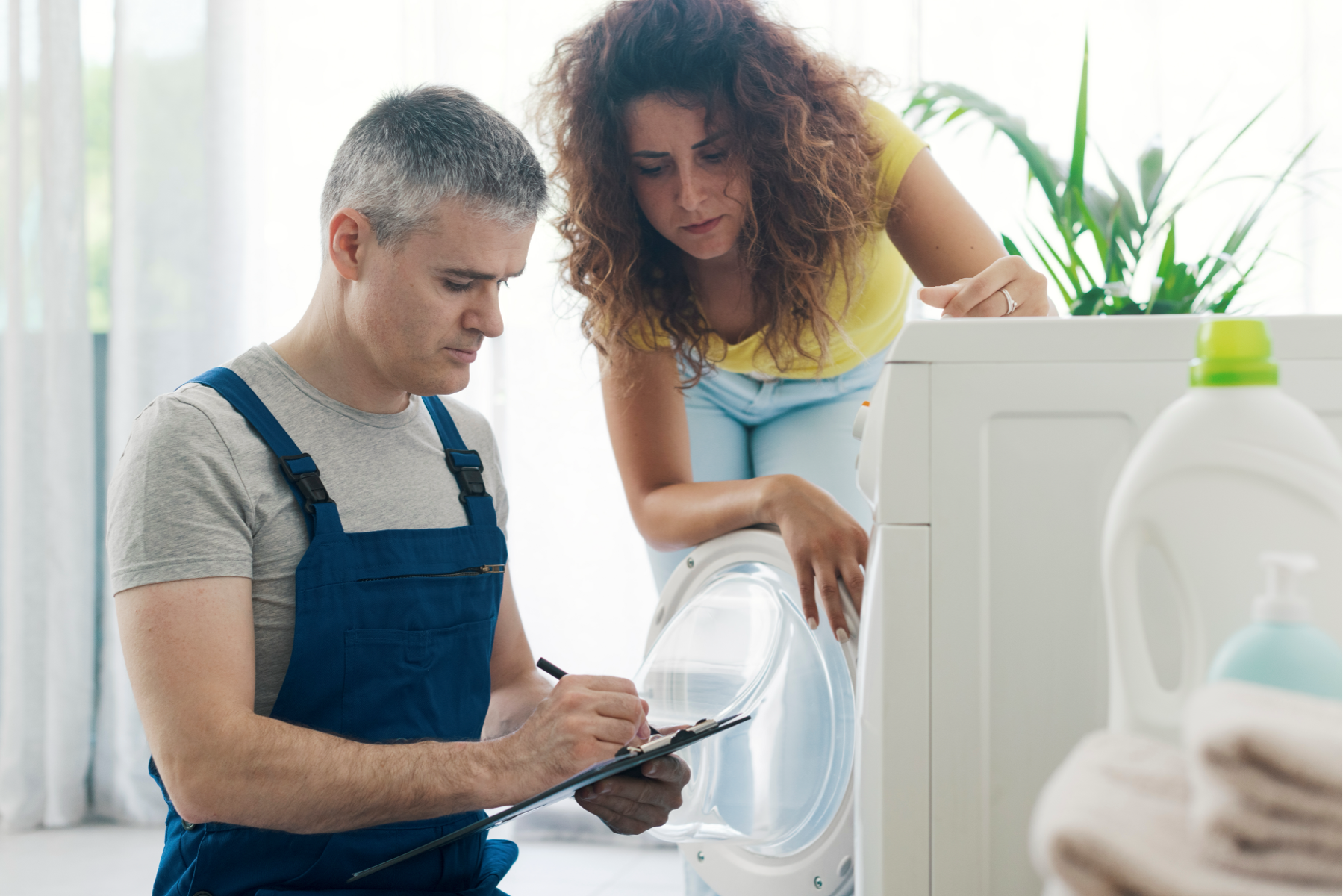 Engineer writing up a washing machine repair with the customer